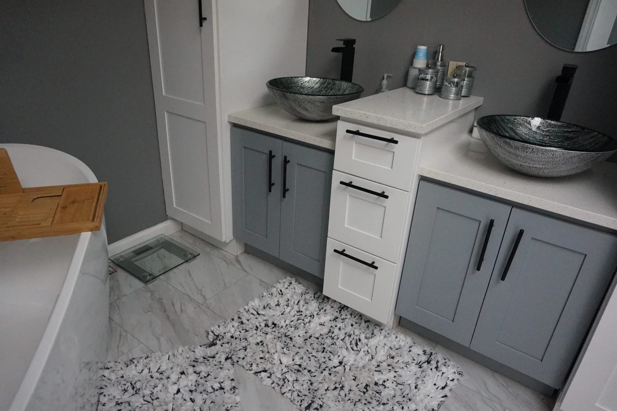 Modern bathroom interior with dual vessel sinks and a freestanding bathtub.